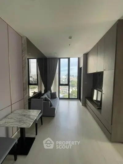 Modern living room with large windows and city view, featuring sleek furniture and elegant decor.