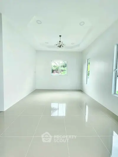 Spacious and bright living room with elegant chandelier and large windows.