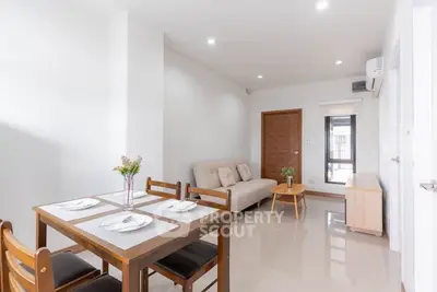 Modern living room with dining area, featuring sleek furniture and bright natural lighting.