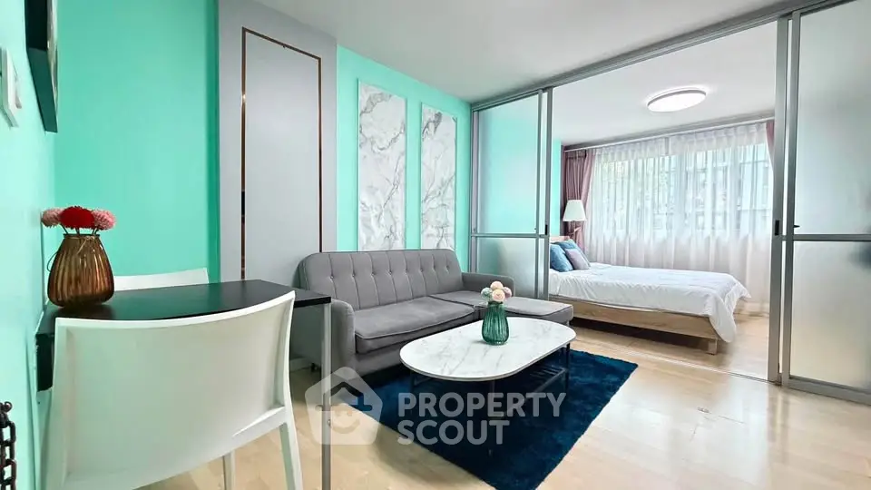 Modern living room with teal accents and sliding doors leading to a cozy bedroom.