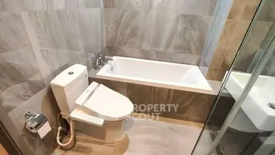 Modern bathroom with sleek tiles and a built-in bathtub, perfect for relaxation.