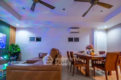 Spacious living room with modern decor and dining area, featuring ceiling fans and ambient lighting.