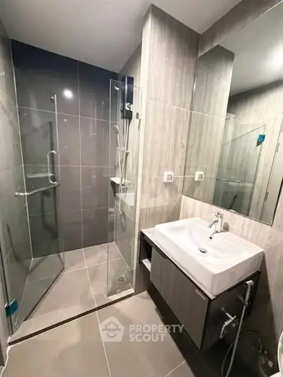 Modern bathroom with sleek glass shower and stylish vanity in contemporary apartment.