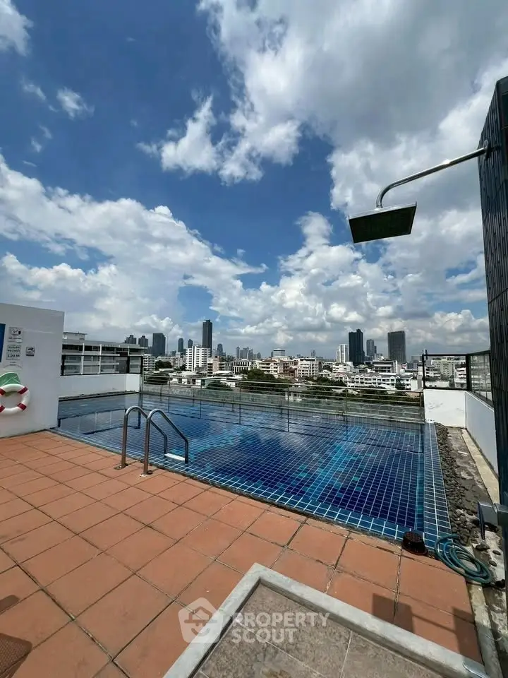 Stunning rooftop pool with city skyline views under a bright blue sky.