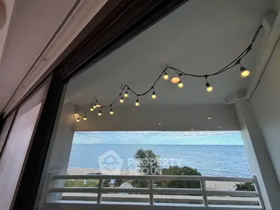Stunning balcony view with ocean backdrop and decorative string lights, perfect for relaxation.
