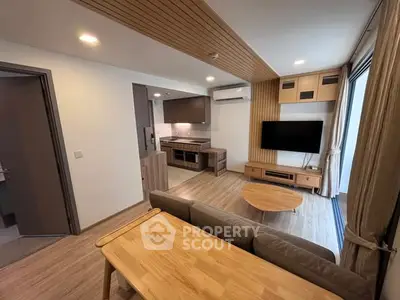 Modern living room with open kitchen, wooden accents, and natural light.
