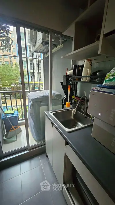 Modern kitchen with balcony view, sleek countertops, and ample storage in urban apartment