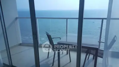Stunning ocean view from a modern balcony with glass railing and outdoor seating.