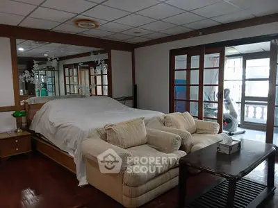 Spacious bedroom with cozy seating area and large windows for natural light.