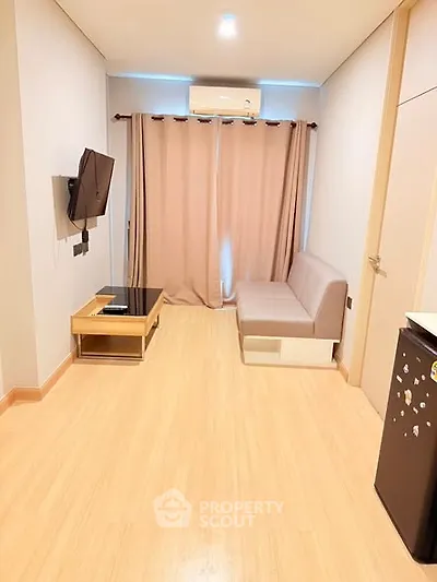 Modern living room with wooden flooring, wall-mounted TV, and cozy sofa in a stylish apartment.