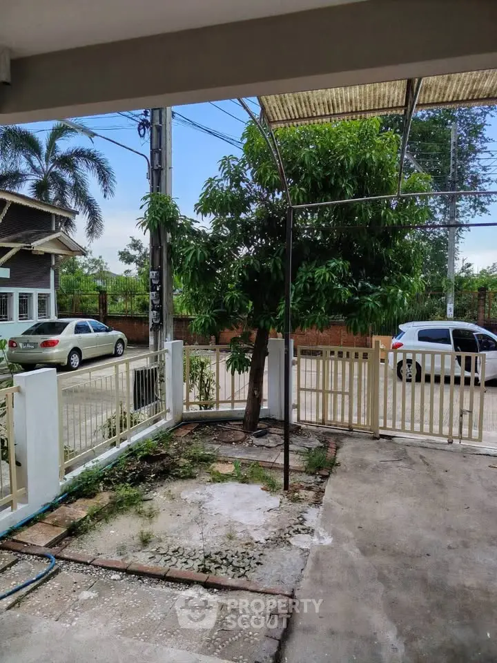 Charming residential driveway with lush greenery and secure gated entrance in a serene neighborhood.