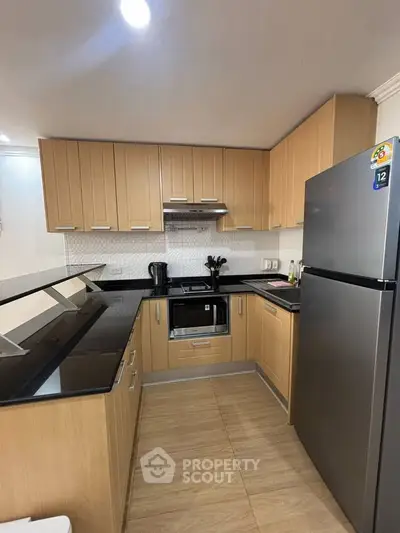 Modern kitchen with sleek wooden cabinets and stainless steel appliances in a cozy apartment.
