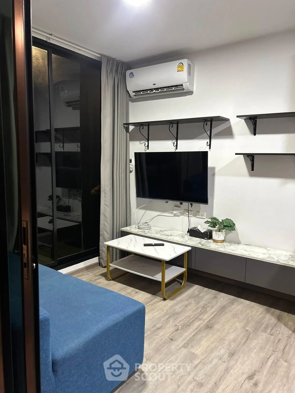 Modern living room with sleek design, featuring a wall-mounted TV, air conditioning, and stylish shelving.