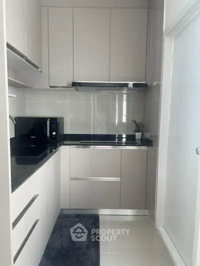 Modern kitchen with sleek cabinetry and black countertops in a compact layout.