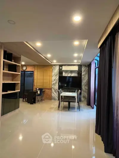 Modern living room with sleek design and open layout, featuring stylish shelving and elegant lighting.