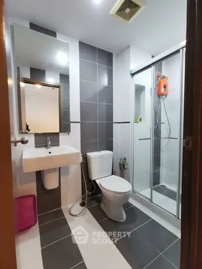 Modern bathroom with sleek design, featuring a glass shower enclosure and stylish tile work.