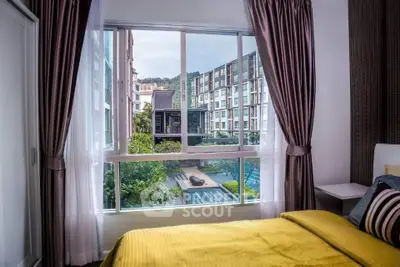 Cozy bedroom with a stunning view of pool and modern buildings through large window.