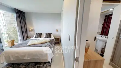 Modern bedroom with cozy decor and adjacent bathroom in stylish apartment.