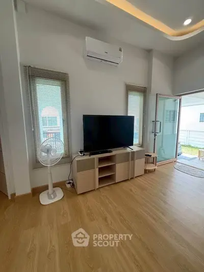 Modern living room with wooden flooring, air conditioning, and large TV setup.