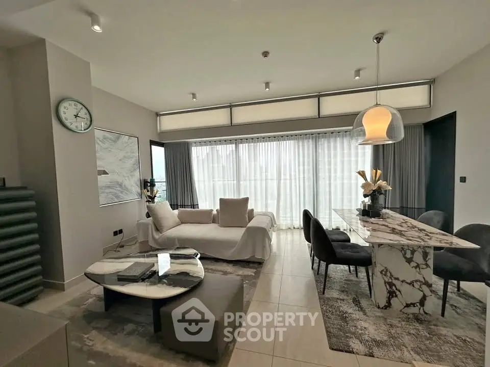 Luxurious modern living room with elegant marble dining table and plush seating, featuring floor-to-ceiling windows.