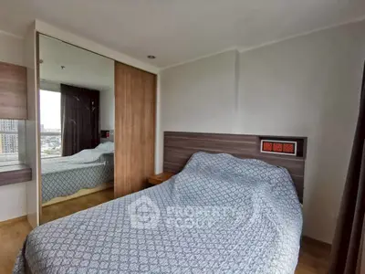 Cozy bedroom with mirrored closet and city view, perfect for urban living.