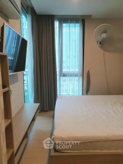 Modern bedroom with large window and wall-mounted TV in urban apartment