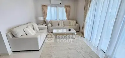 Elegant living room with plush sofas and natural light, perfect for relaxation and entertaining.