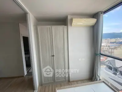 Bright bedroom with large window and air conditioning, offering a scenic city view.