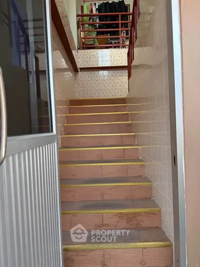 Charming staircase with tiled steps leading to upper level in cozy home.