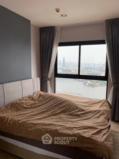 Cozy bedroom with stunning city view through large window, modern decor and natural light.