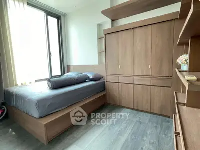 Modern bedroom with sleek wooden furniture and large window for natural light.