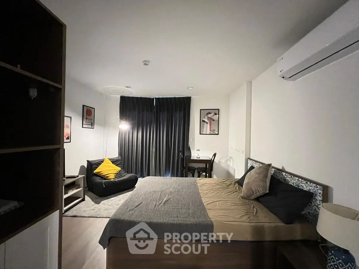 Modern bedroom with cozy decor and natural light, featuring a stylish bed and seating area.