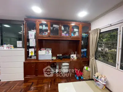 Spacious living room with elegant wooden storage and large window view.