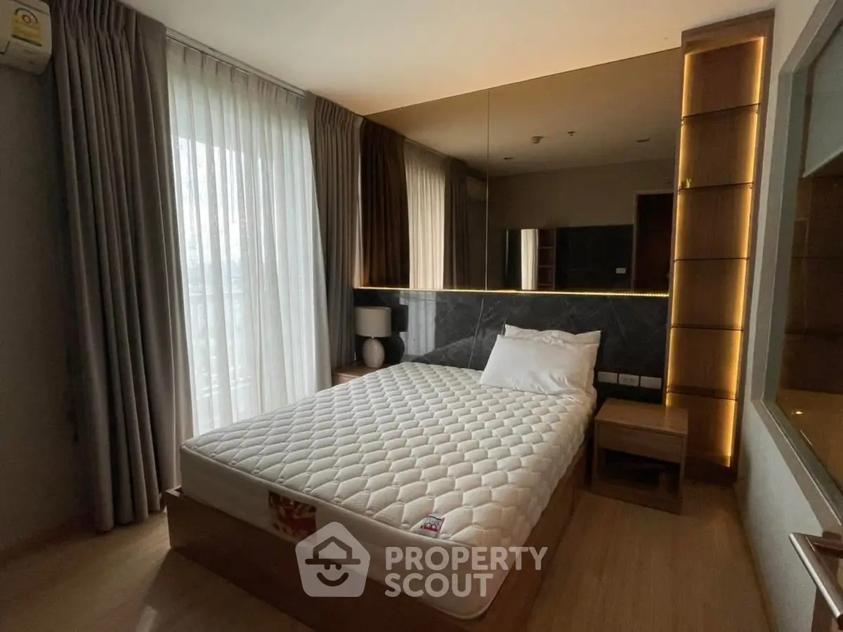 Modern bedroom with large window and stylish lighting in a contemporary apartment.