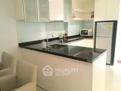 Modern kitchen with sleek black countertops and built-in appliances in a stylish apartment.