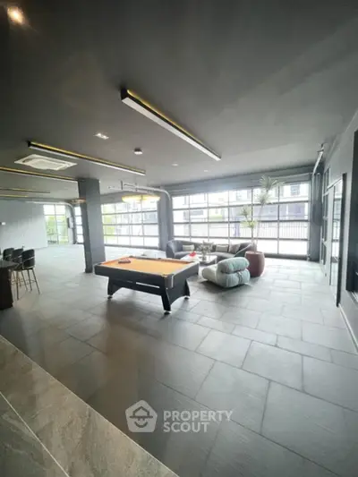 Spacious modern living area with pool table and large windows, perfect for entertainment and relaxation.