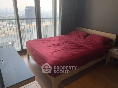 Spacious bedroom with city view and elegant red bedding in modern apartment