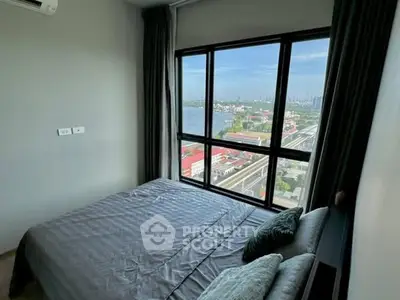 Cozy bedroom with stunning river view and large window in modern apartment.