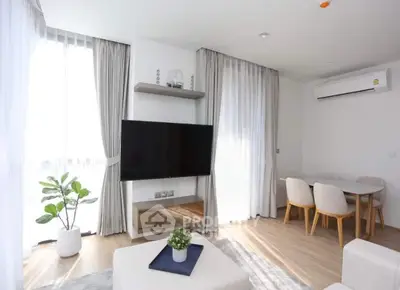 Bright modern living room with large TV, dining area, and stylish decor
