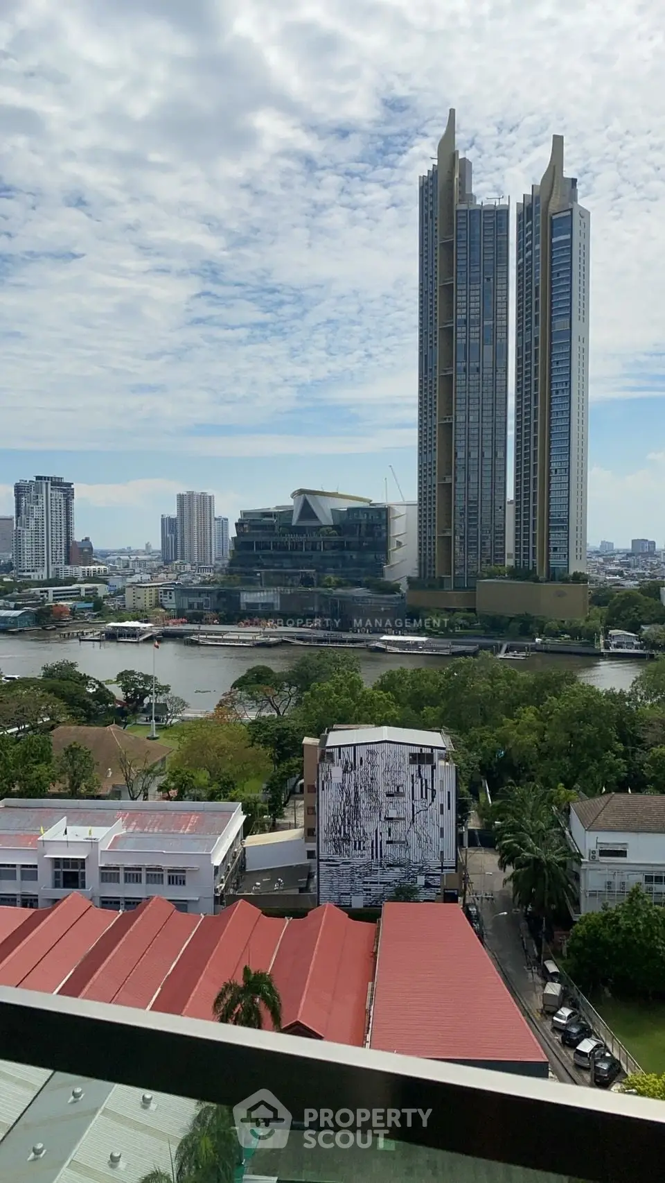 Stunning cityscape view with modern high-rise buildings and lush greenery by the river.