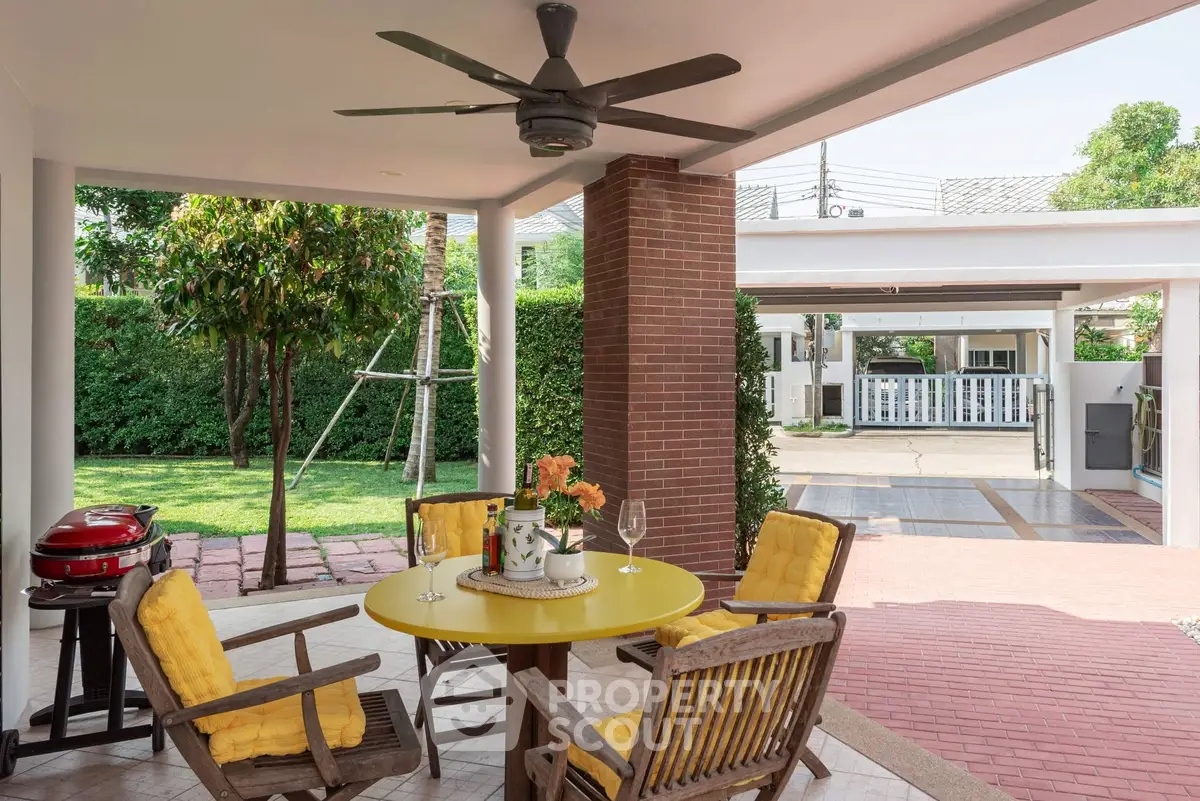 Charming outdoor patio with garden view, featuring a cozy seating area and vibrant yellow accents.