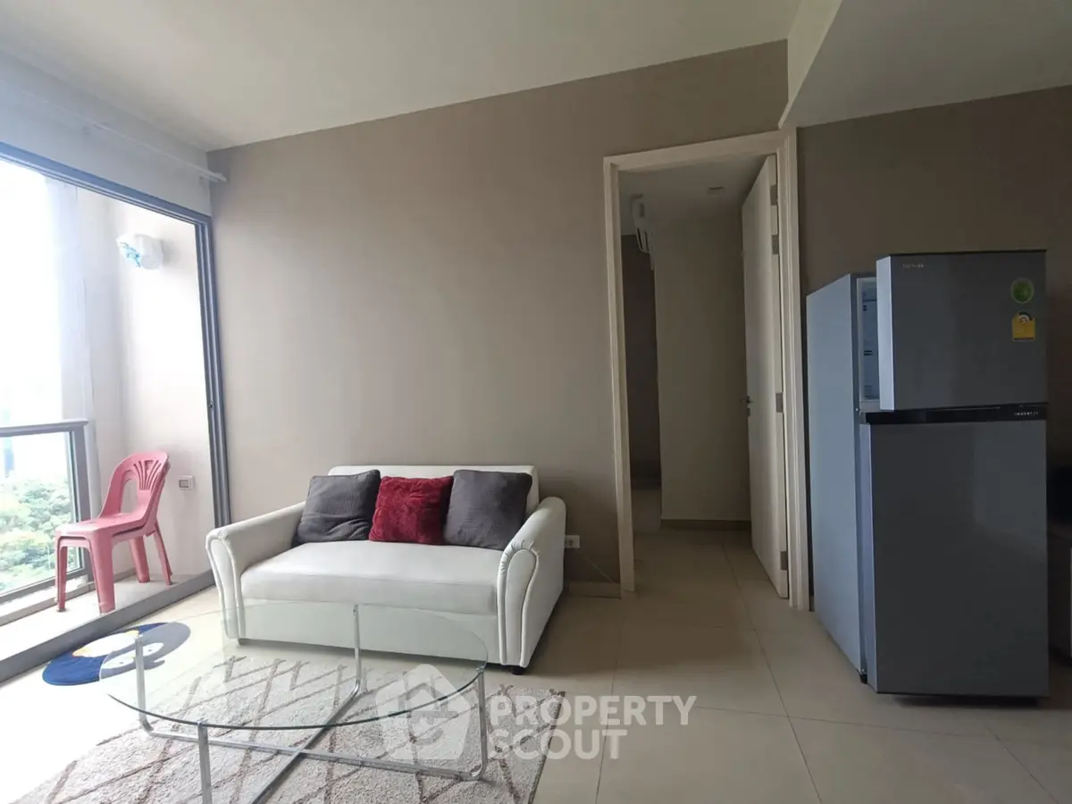 Modern living room with white sofa, glass coffee table, and balcony view