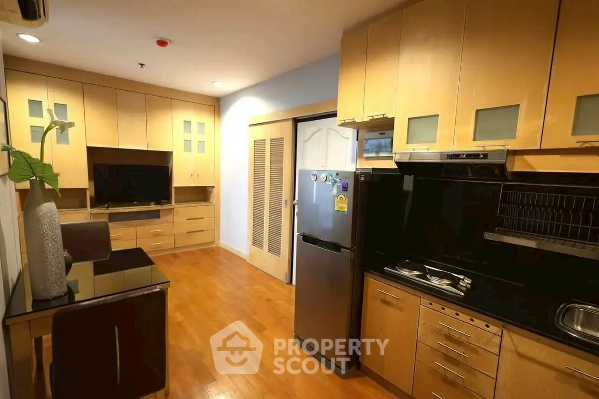 Spacious kitchen with modern appliances and wooden cabinetry in a cozy apartment.