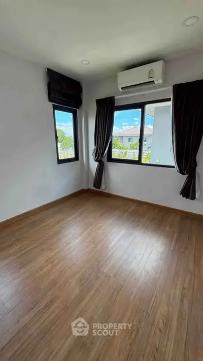 Spacious bedroom with wooden flooring and large windows offering natural light and scenic views.