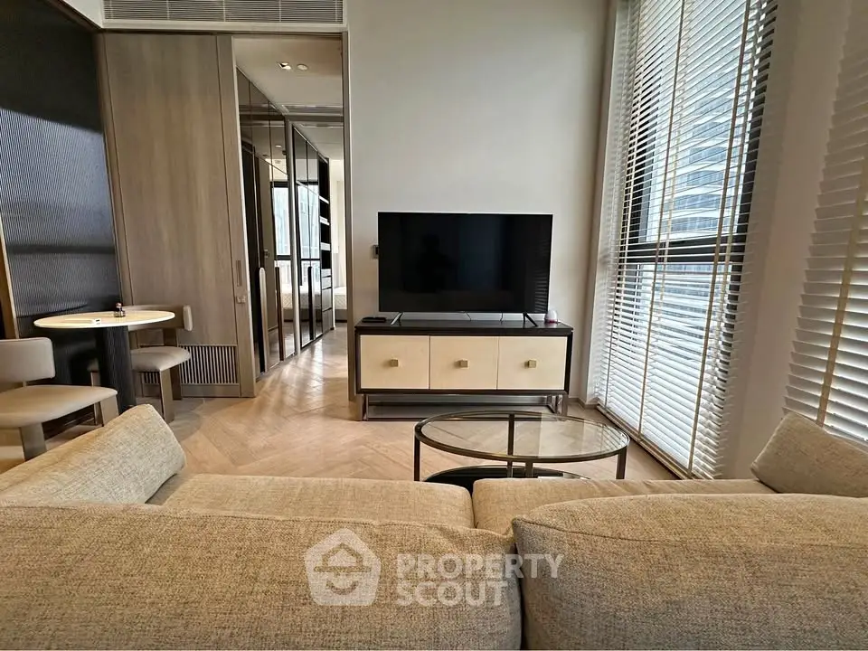 Modern living room with stylish furniture and large window offering city views.