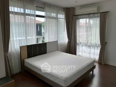 Spacious bedroom with large windows and modern decor in a serene residential area.