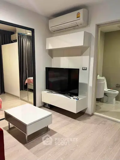 Modern living room with sleek TV unit and air conditioning, adjacent to a cozy bedroom and bathroom.