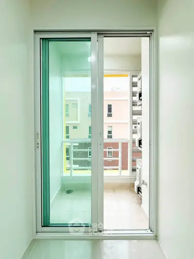 Bright balcony with sliding glass doors and urban view, perfect for relaxation.