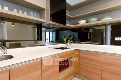 Modern kitchen with sleek cabinetry and built-in microwave, featuring open shelving and stylish decor.