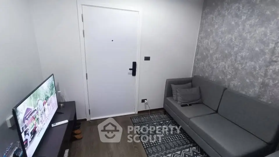 Cozy living room with modern gray sofa and TV, featuring stylish decor and wooden flooring.